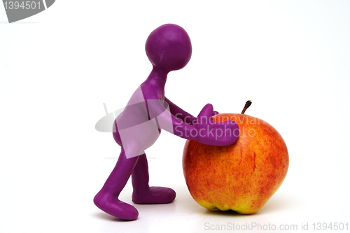 Image of Purple puppet of plasticine pushing done apple