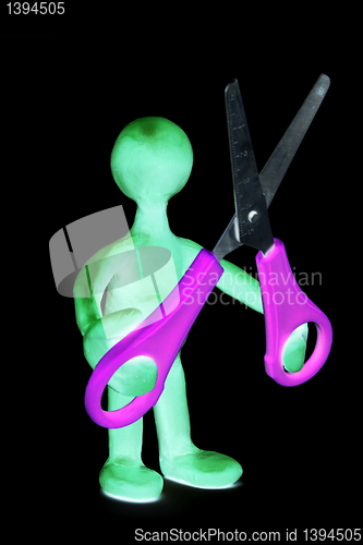 Image of Shaded puppet of plasticine holding green scissors