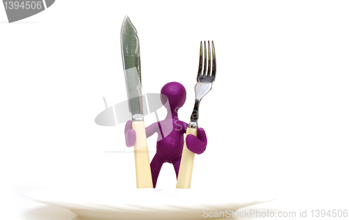 Image of Purple puppet of plasticine standing behind plate