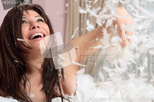 Image of Fun woman throwing handful of feather and down