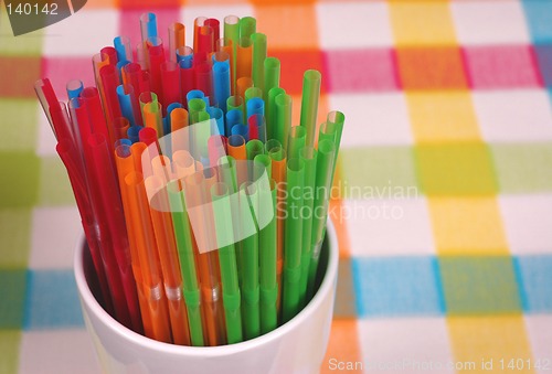 Image of Colorful straws in white glass on checkered mat