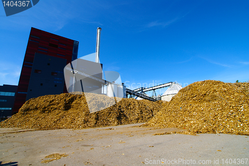 Image of bio power plant with storage of wooden fuel against blue sky