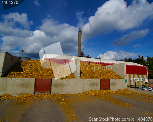 Image of bio power plant with storage of wooden fuel against blue sky