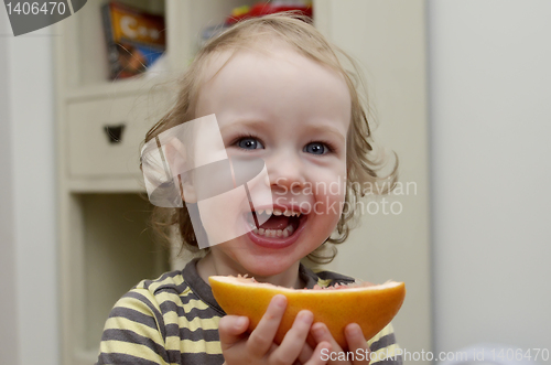 Image of little girl laughing and eating grapefruit