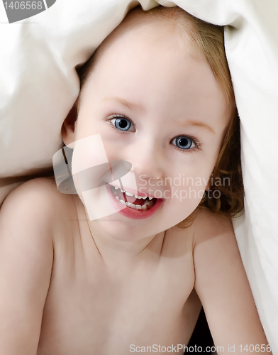 Image of little girl looking out from under blanket