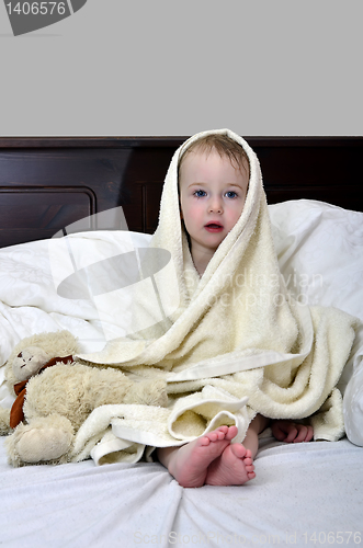 Image of little girl in a towel after a shower resting on a bed