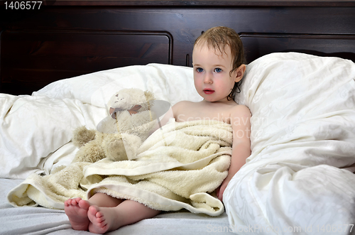 Image of little girl in a towel after a shower resting on a bed