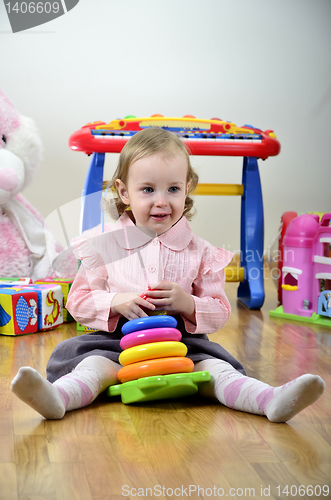Image of little girl in a room with toys, playing with color pyramid