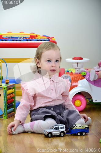 Image of little girl in a room with toys, playing with cars