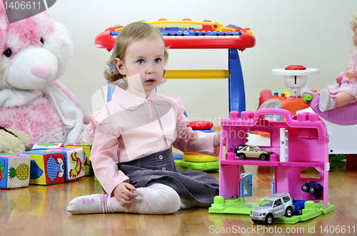 Image of little girl in a room with toys, playing with cars