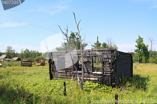 Image of burned rural house on green field