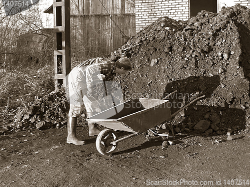 Image of worker loads coal on wheelbarrow 