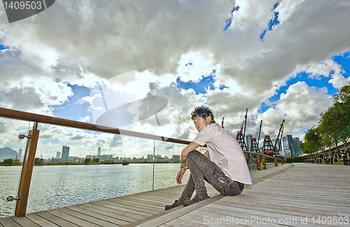 Image of asian man sitting in park