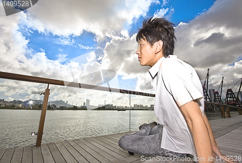 Image of asian man sitting in park