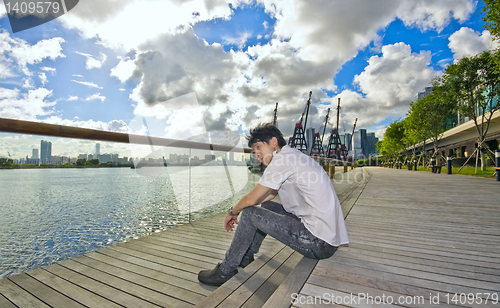 Image of asian man sitting in park