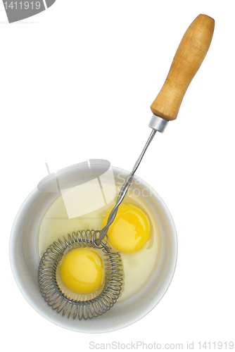 Image of Crude eggs in a plate and mixer with the wooden handle.