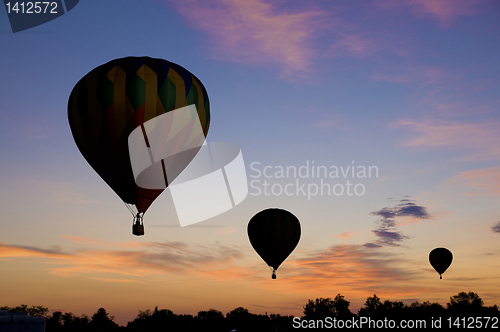 Image of Hot-air balloons floating against a reddish dawn sky