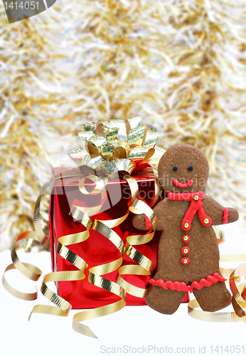 Image of Gingerbread man cookie with a red scarf standing next to Christm