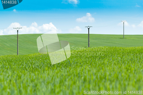 Image of high voltage power lines in field against a blue sky 