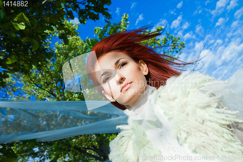 Image of beautiful woman in white against blue sky and green trees