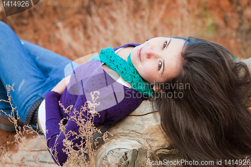 Image of Shot of a young woman lying on log 