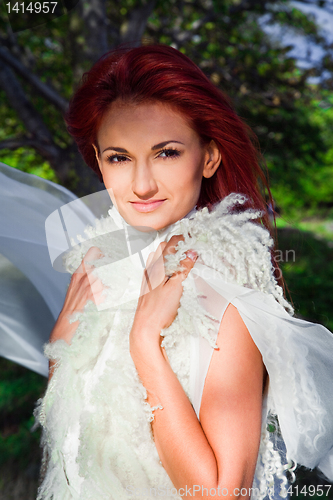 Image of beautiful woman in white against blue sky and green trees