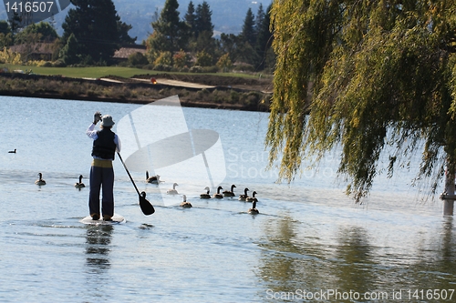 Image of Man on paddle-board with mountain, lake and trees