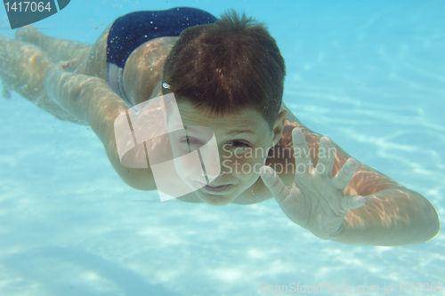 Image of Boy swimming underwater in swimming pool 