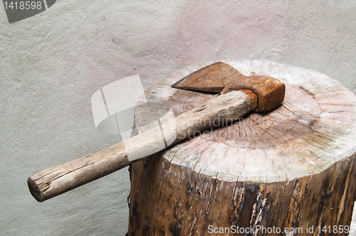 Image of The old rusty axe lays on a log