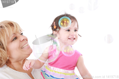 Image of Aunt and a little girl enjoy looking at bubbles floating in the 