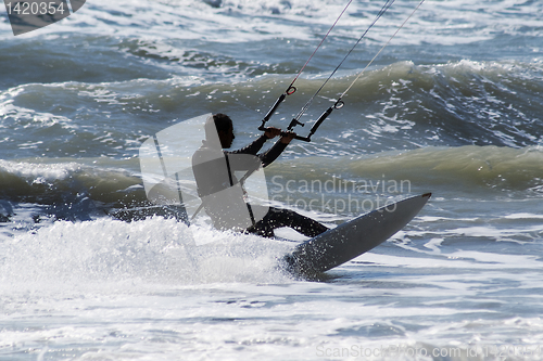 Image of Silhouette of kite surfer jumping over the waves