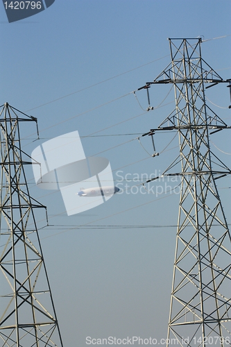 Image of Blimp floating between two pylons and above power lines