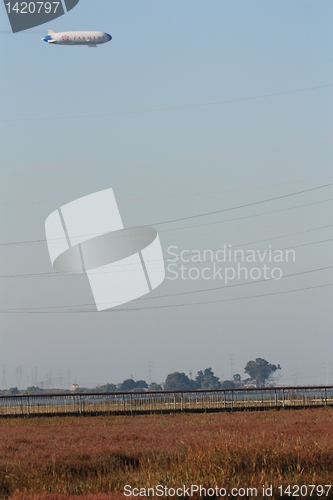 Image of Blimp floating above the marshland and power lines