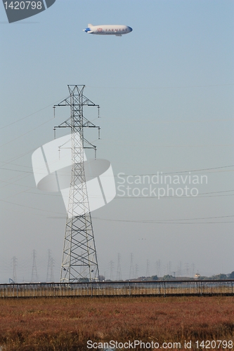 Image of Blimp floating above the marshland and a pylon