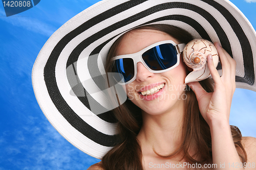 Image of woman listens seashell