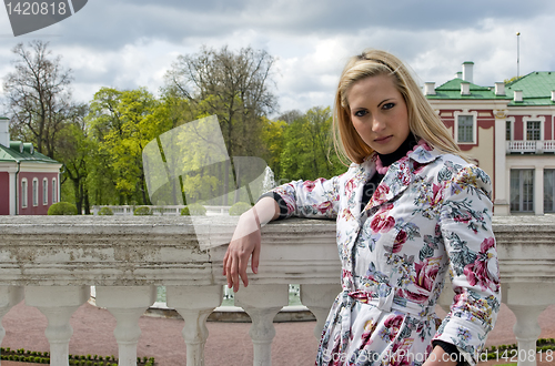 Image of blonde girl standing against the background of an old palace