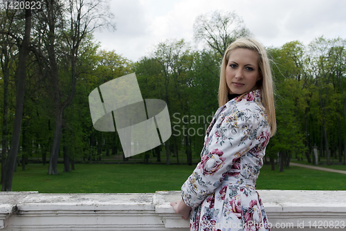Image of blonde girl standing against a background of park
