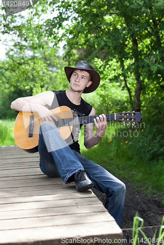 Image of man playing guitar in the woods
