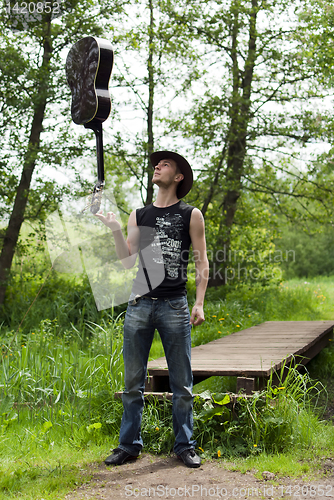 Image of man holding a guitar on his finger 