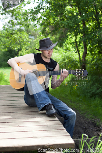Image of man playing guitar in the woods