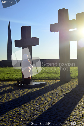 Image of Girl praying at the Crosses at sunset