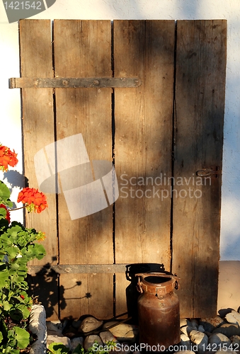 Image of Milk jug in front a wooden gate