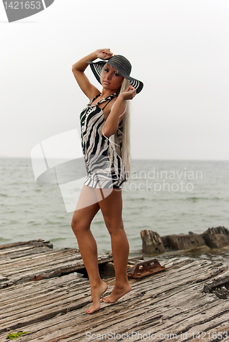 Image of girl in a hat standing on a broken ship at sea