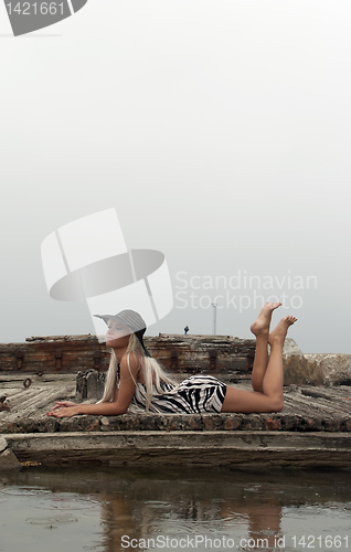 Image of girl in a hat sitting on a broken ship at sea