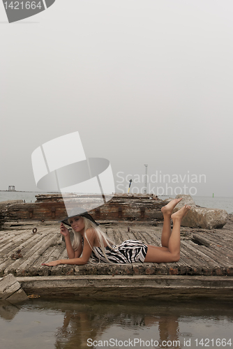 Image of girl in a hat lying on a broken ship at sea