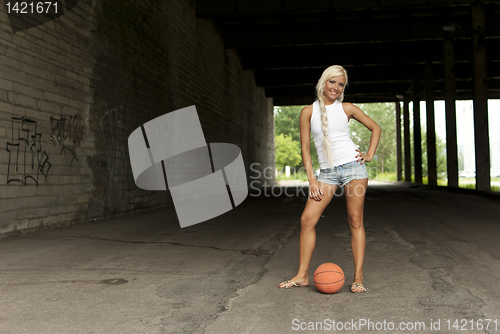 Image of Beautiful blonde girl standing with basketball in the street