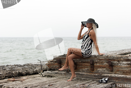 Image of girl in a hat sitting on a broken ship at sea