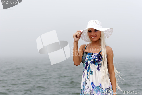 Image of Girl in hat standing in the misty sea