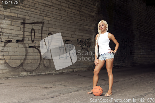 Image of Beautiful blonde girl standing with basketball in the street