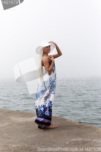 Image of Girl in hat standing in the misty sea